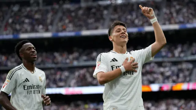 Real Madrid formasıyla Arda Güler, attığı golün ardından eli göğsünde ve parmağı havada sevinirken; arkada Vinicius Junior