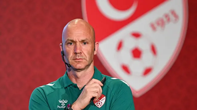 Anthony Taylor, TFF logolu kırmızı panonun önünde kulaklıklı mikrofonla konuşurken