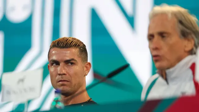 Cristiano Ronaldo basın toplantısında yan tarafa bakıyor; sağda bulanık görüntüde Jorge Jesus konuşuyor