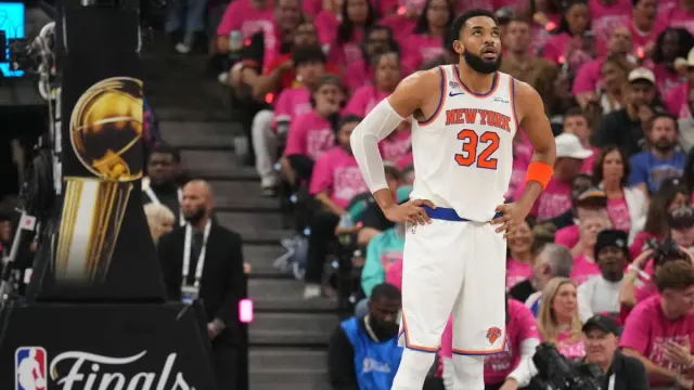 New York Knicks formalı Karl-Anthony Towns, NBA Finalleri kupasının yanında bellerinde elleriyle bekliyor
