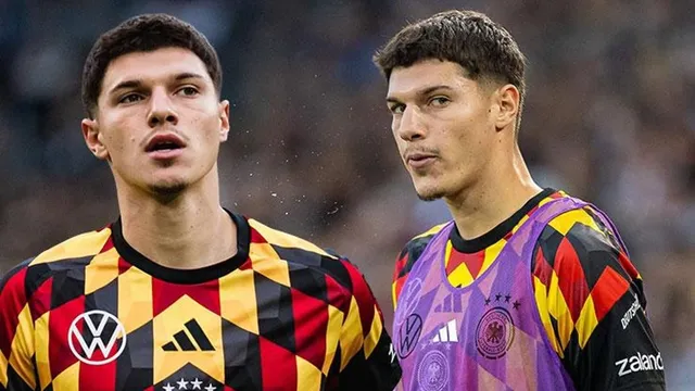 Almanya milli takımı forması ve ısınma yeleğiyle iki genç futbolcu yan yana sahada