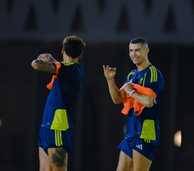 Al Nassr'ın lacivert-sarı antrenman formasıyla Cristiano Ronaldo, turuncu yeleğini çıkarırken gülümsüyor
