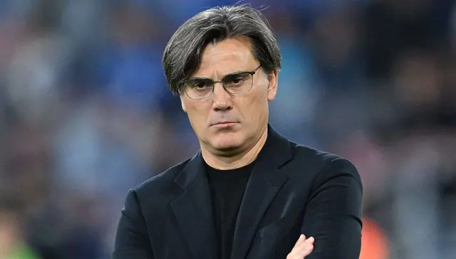 Gözlüklü Vincenzo Montella, kollarını kavuşturmuş ciddi bir ifadeyle kameraya bakıyor