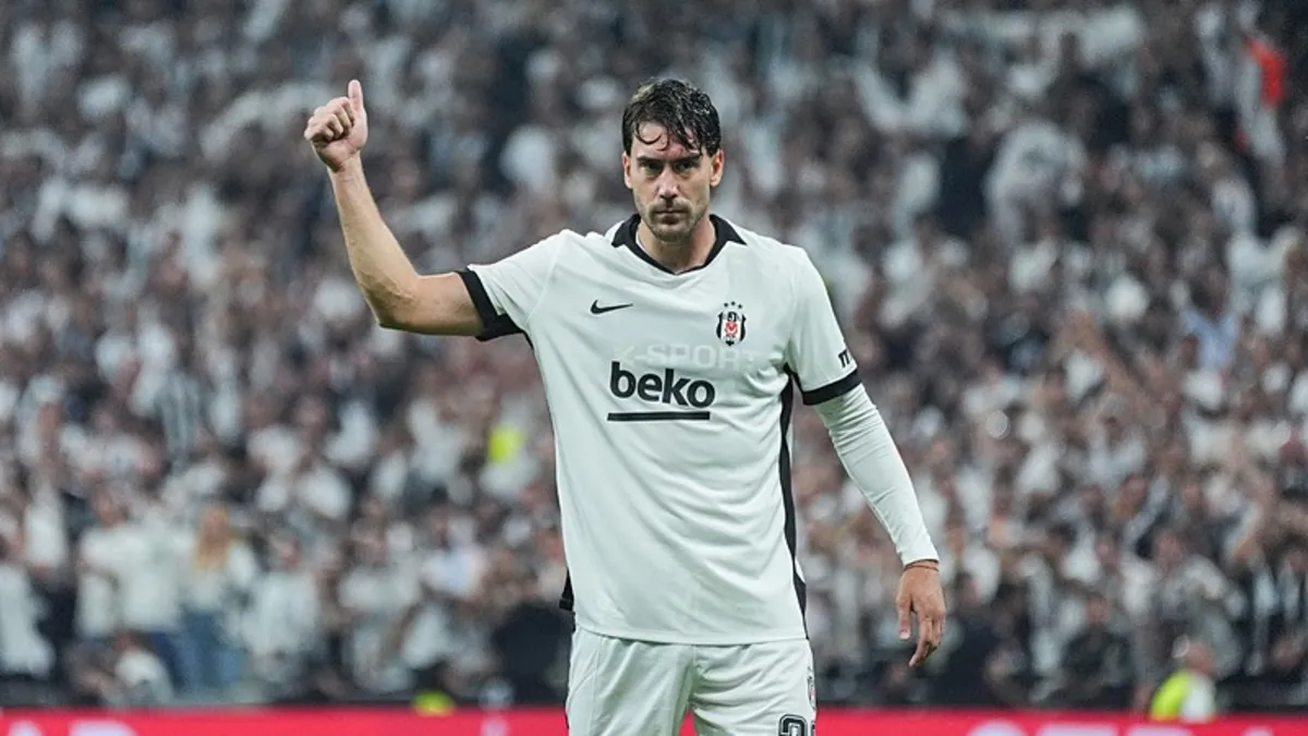 Beşiktaş'ın beyaz formasıyla Dusan Vlahovic, dolu tribünün önünde başparmağını kaldırıyor