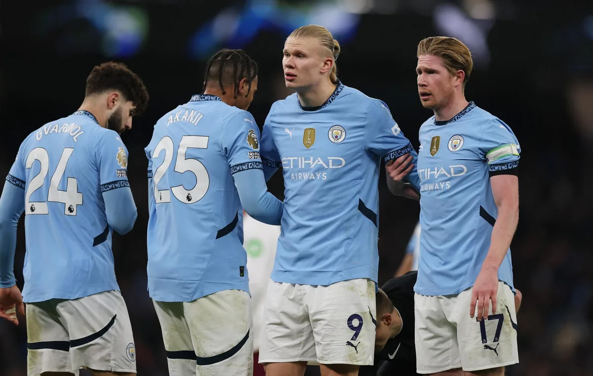 Açık mavi formalı Manchester City oyuncuları maç sırasında sahada yan yana duruyor