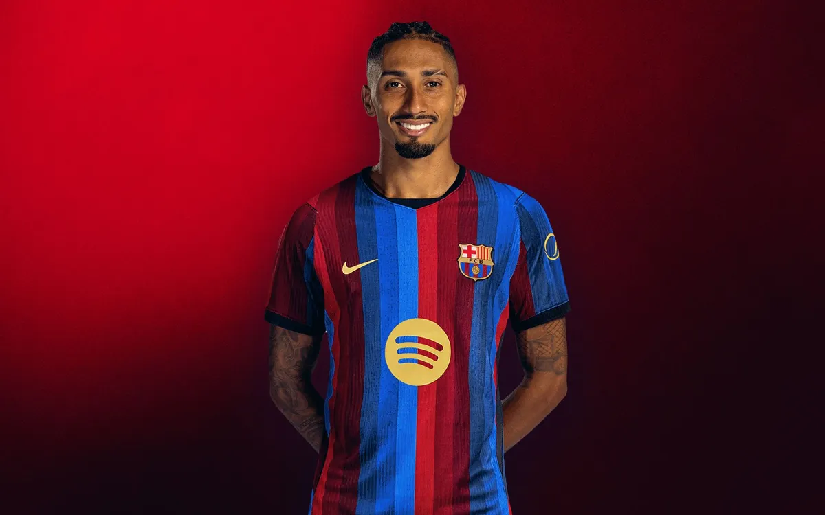 Barcelona formalı Raphinha, kırmızı fonun önünde gülümseyerek poz veriyor
